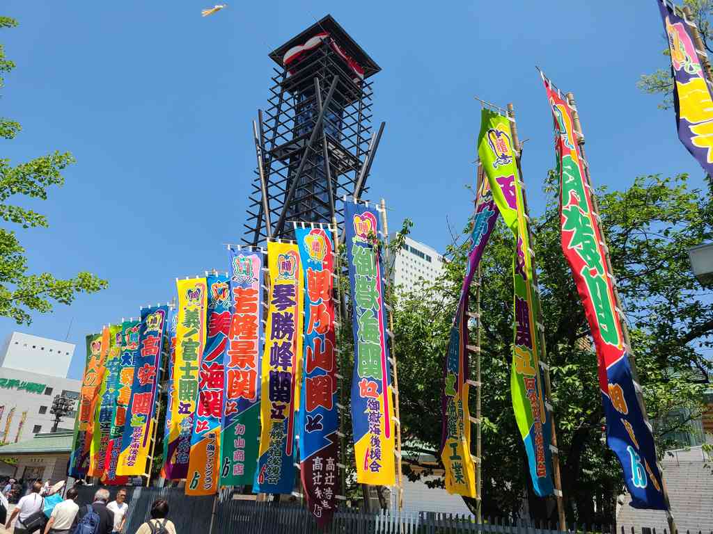 Outside the Kokugikan (sumo stadium) proudly fly the colorful flags of the upper-division wrestlers. The drum tower in the background is where drummers traditionally announce the start and end of the day's matches.